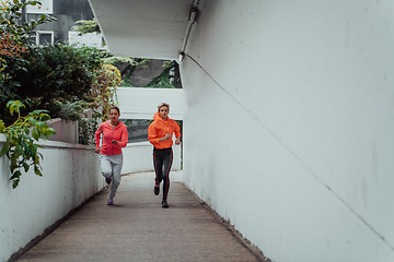 Image showing Two women in sports clothes running in a modern urban environment. The concept of a sporty and healthy lifestyle