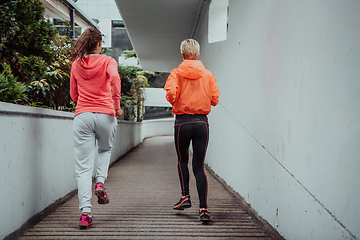 Image showing Two women in sports clothes running in a modern urban environment. The concept of a sporty and healthy lifestyle