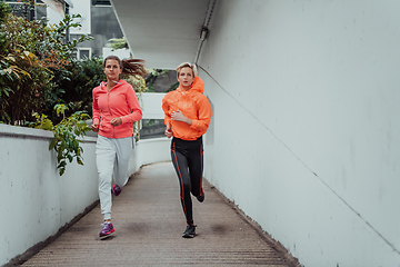 Image showing Two women in sports clothes running in a modern urban environment. The concept of a sporty and healthy lifestyle