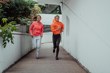 Image showing Two women in sports clothes running in a modern urban environment. The concept of a sporty and healthy lifestyle