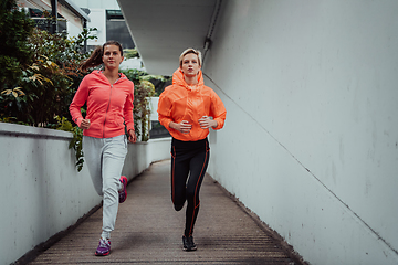 Image showing Two women in sports clothes running in a modern urban environment. The concept of a sporty and healthy lifestyle