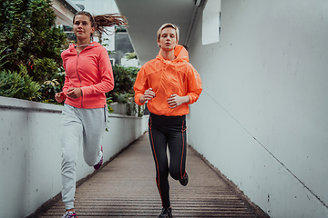 Image showing Two women in sports clothes running in a modern urban environment. The concept of a sporty and healthy lifestyle