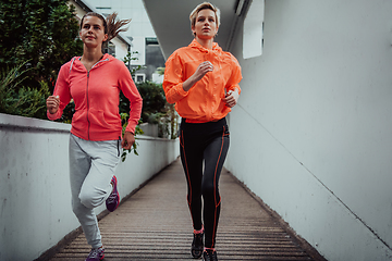 Image showing Two women in sports clothes running in a modern urban environment. The concept of a sporty and healthy lifestyle