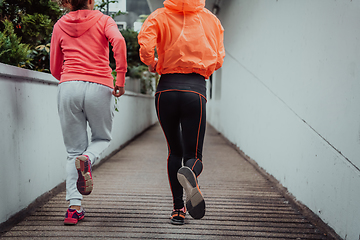 Image showing Two women in sports clothes running in a modern urban environment. The concept of a sporty and healthy lifestyle