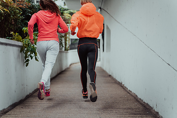 Image showing Two women in sports clothes running in a modern urban environment. The concept of a sporty and healthy lifestyle