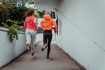 Image showing Two women in sports clothes running in a modern urban environment. The concept of a sporty and healthy lifestyle