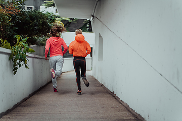 Image showing Two women in sports clothes running in a modern urban environment. The concept of a sporty and healthy lifestyle