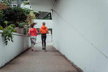 Image showing Two women in sports clothes running in a modern urban environment. The concept of a sporty and healthy lifestyle