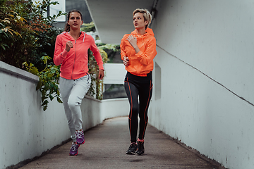 Image showing Two women in sports clothes running in a modern urban environment. The concept of a sporty and healthy lifestyle