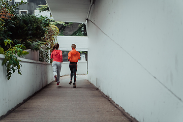 Image showing Two women in sports clothes running in a modern urban environment. The concept of a sporty and healthy lifestyle