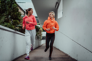 Image showing Two women in sports clothes running in a modern urban environment. The concept of a sporty and healthy lifestyle