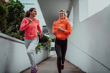 Image showing Two women in sports clothes running in a modern urban environment. The concept of a sporty and healthy lifestyle