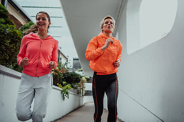 Image showing Two women in sports clothes running in a modern urban environment. The concept of a sporty and healthy lifestyle