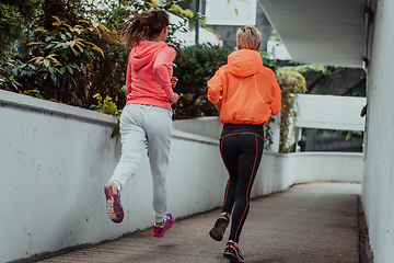 Image showing Two women in sports clothes running in a modern urban environment. The concept of a sporty and healthy lifestyle