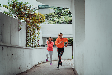 Image showing Two women in sports clothes running in a modern urban environment. The concept of a sporty and healthy lifestyle