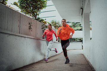 Image showing Two women in sports clothes running in a modern urban environment. The concept of a sporty and healthy lifestyle