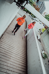 Image showing Two women in sports clothes running in a modern urban environment. The concept of a sporty and healthy lifestyle