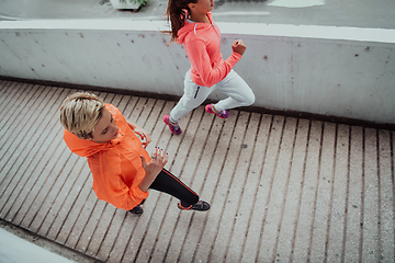 Image showing Two women in sports clothes running in a modern urban environment. The concept of a sporty and healthy lifestyle