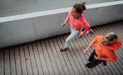 Image showing Two women in sports clothes running in a modern urban environment. The concept of a sporty and healthy lifestyle