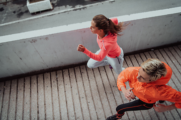 Image showing Two women in sports clothes running in a modern urban environment. The concept of a sporty and healthy lifestyle