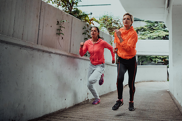 Image showing Two women in sports clothes running in a modern urban environment. The concept of a sporty and healthy lifestyle