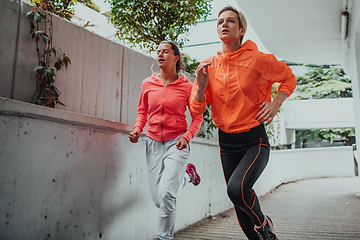 Image showing Two women in sports clothes running in a modern urban environment. The concept of a sporty and healthy lifestyle