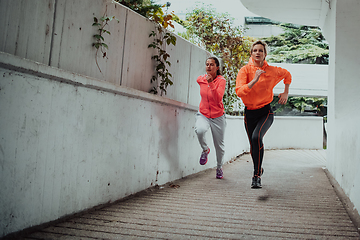 Image showing Two women in sports clothes running in a modern urban environment. The concept of a sporty and healthy lifestyle