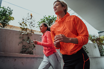 Image showing Two women in sports clothes running in a modern urban environment. The concept of a sporty and healthy lifestyle