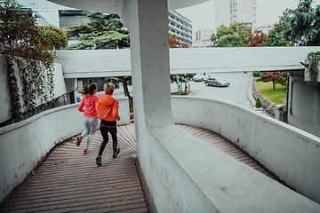 Image showing Two women in sports clothes running in a modern urban environment. The concept of a sporty and healthy lifestyle