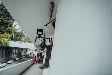 Image showing A professional cameraman with equipment and a stabilizer recoding two woman for a commercial advertisement as they run in an urban environment