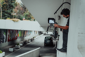 Image showing A professional cameraman with equipment and a stabilizer recoding two woman for a commercial advertisement as they run in an urban environment