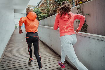 Image showing Two women in sports clothes running in a modern urban environment. The concept of a sporty and healthy lifestyle