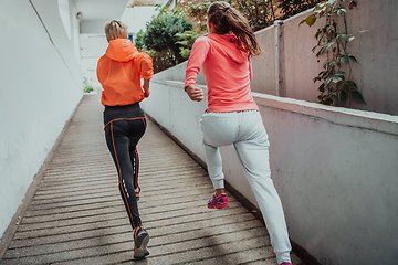 Image showing Two women in sports clothes running in a modern urban environment. The concept of a sporty and healthy lifestyle