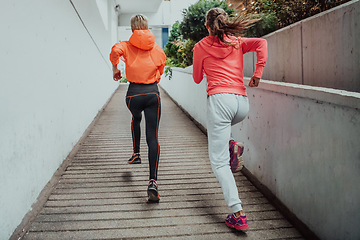 Image showing Two women in sports clothes running in a modern urban environment. The concept of a sporty and healthy lifestyle