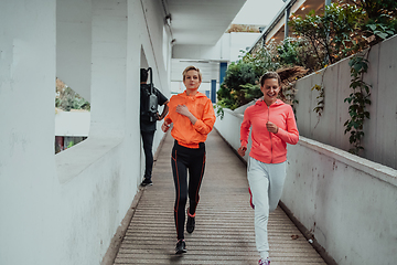 Image showing Two women in sports clothes running in a modern urban environment. The concept of a sporty and healthy lifestyle