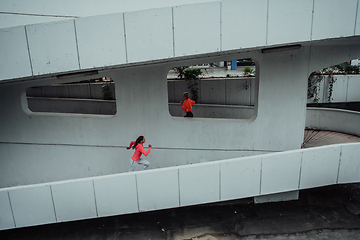 Image showing Two women in sports clothes running in a modern urban environment. The concept of a sporty and healthy lifestyle