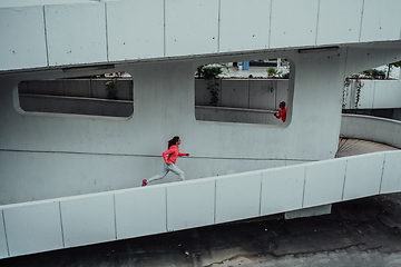 Image showing Two women in sports clothes running in a modern urban environment. The concept of a sporty and healthy lifestyle