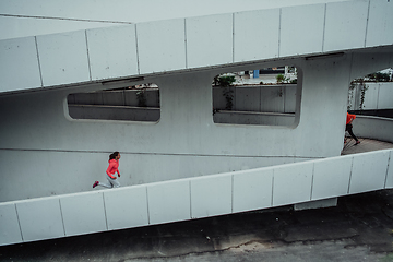 Image showing Two women in sports clothes running in a modern urban environment. The concept of a sporty and healthy lifestyle