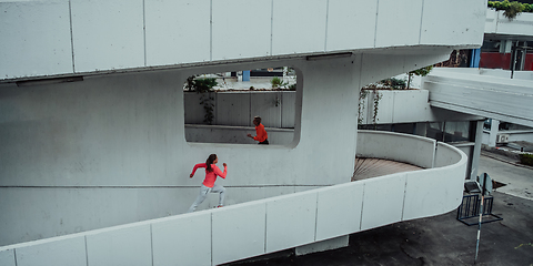 Image showing Two women in sports clothes running in a modern urban environment. The concept of a sporty and healthy lifestyle