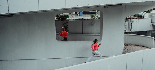 Image showing Two women in sports clothes running in a modern urban environment. The concept of a sporty and healthy lifestyle