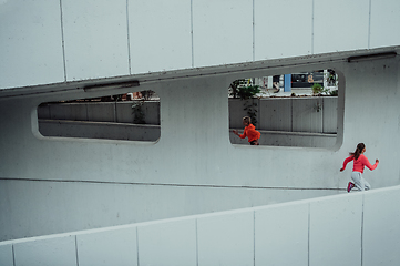 Image showing Two women in sports clothes running in a modern urban environment. The concept of a sporty and healthy lifestyle