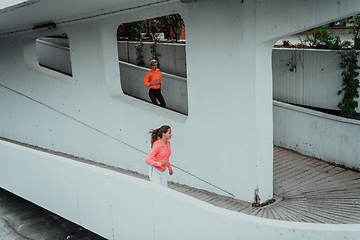 Image showing Two women in sports clothes running in a modern urban environment. The concept of a sporty and healthy lifestyle