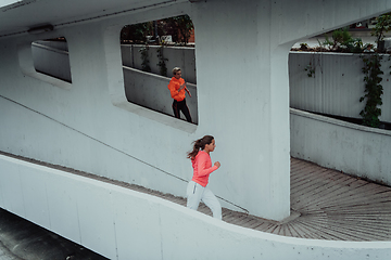 Image showing Two women in sports clothes running in a modern urban environment. The concept of a sporty and healthy lifestyle