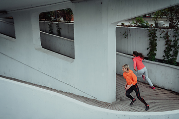 Image showing Two women in sports clothes running in a modern urban environment. The concept of a sporty and healthy lifestyle