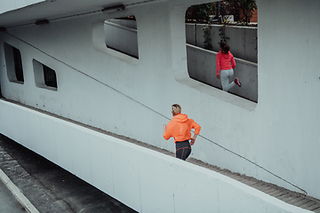 Image showing Two women in sports clothes running in a modern urban environment. The concept of a sporty and healthy lifestyle