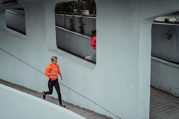 Image showing Two women in sports clothes running in a modern urban environment. The concept of a sporty and healthy lifestyle