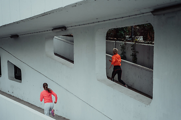 Image showing Two women in sports clothes running in a modern urban environment. The concept of a sporty and healthy lifestyle