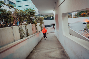 Image showing Women in sports clothes running in a modern urban environment et night time. The concept of a sporty and healthy lifestyle