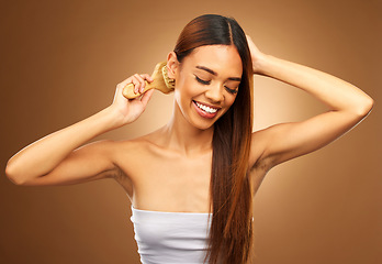 Image showing Brushing hair, beauty and a happy woman in studio for growth, color shine or healthy brunette texture. Female smile for haircare brush, natural self care and hairdresser or salon on brown background