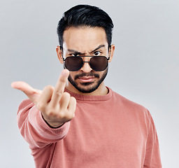 Image showing Hand, middle finger and portrait of man in studio with sunglasses, attitude and gesture against grey background. Face, rebel and emoji by asian male edgy, expression and personality while isolated